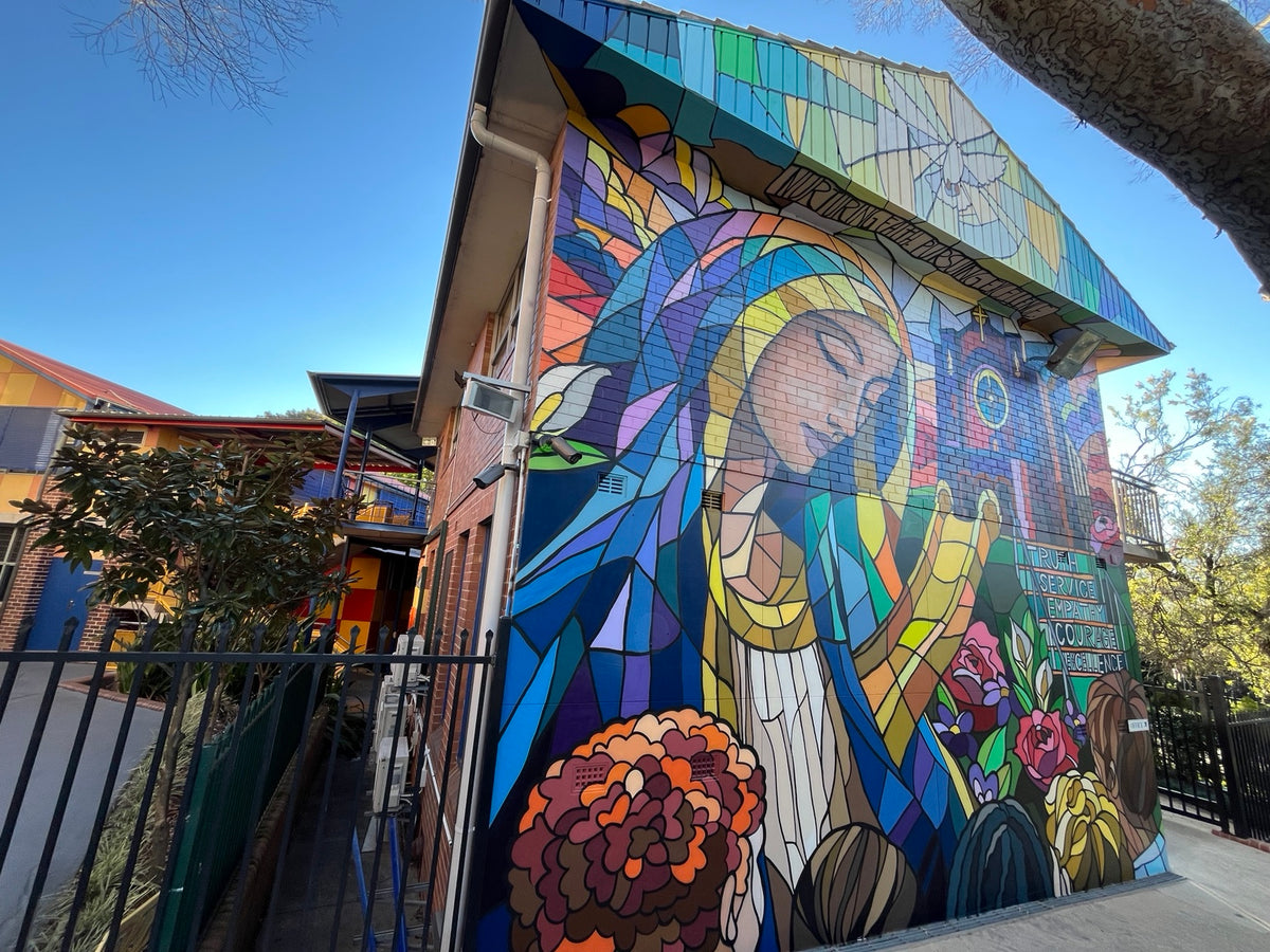 Wide view of DMuly’s stained-glass-style Mary mural across the exterior of St Mary’s Catholic Primary School, Concord